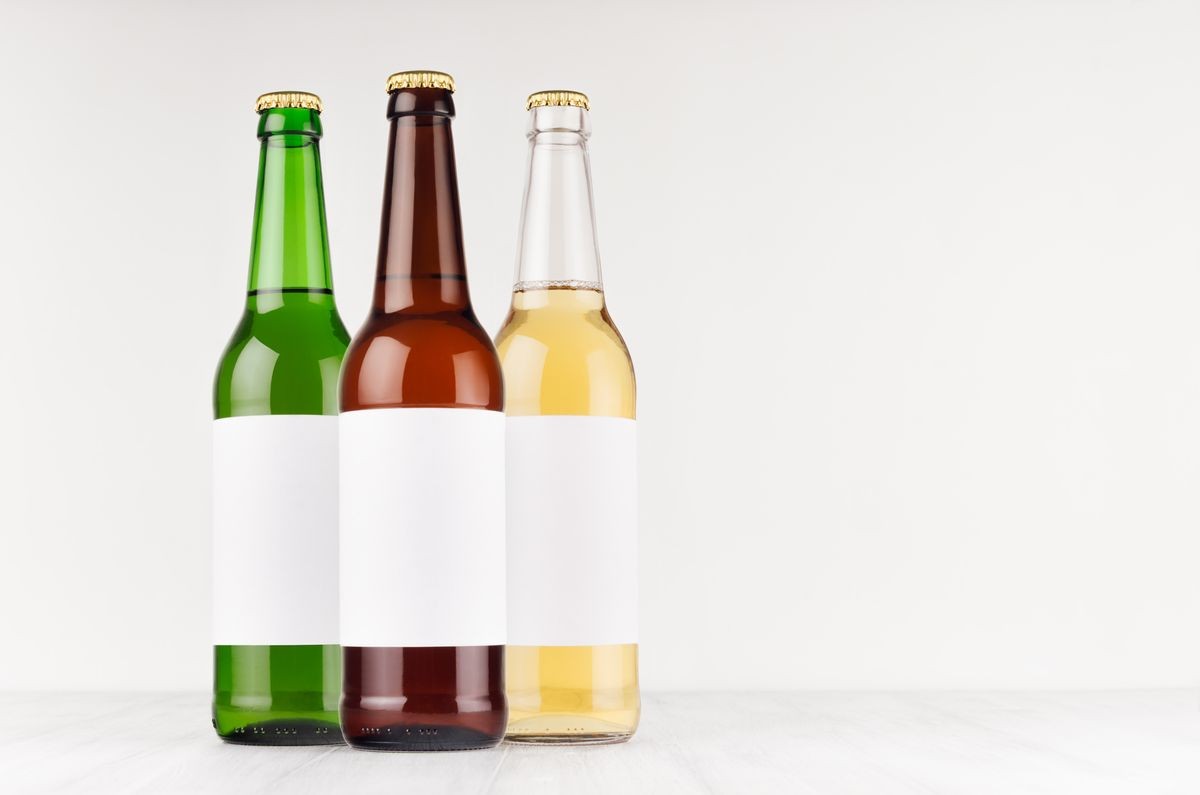 Three beer bottles longneck 500ml different colors with blank white label on white wooden board, mock up. Template for advertising, design, branding identity.